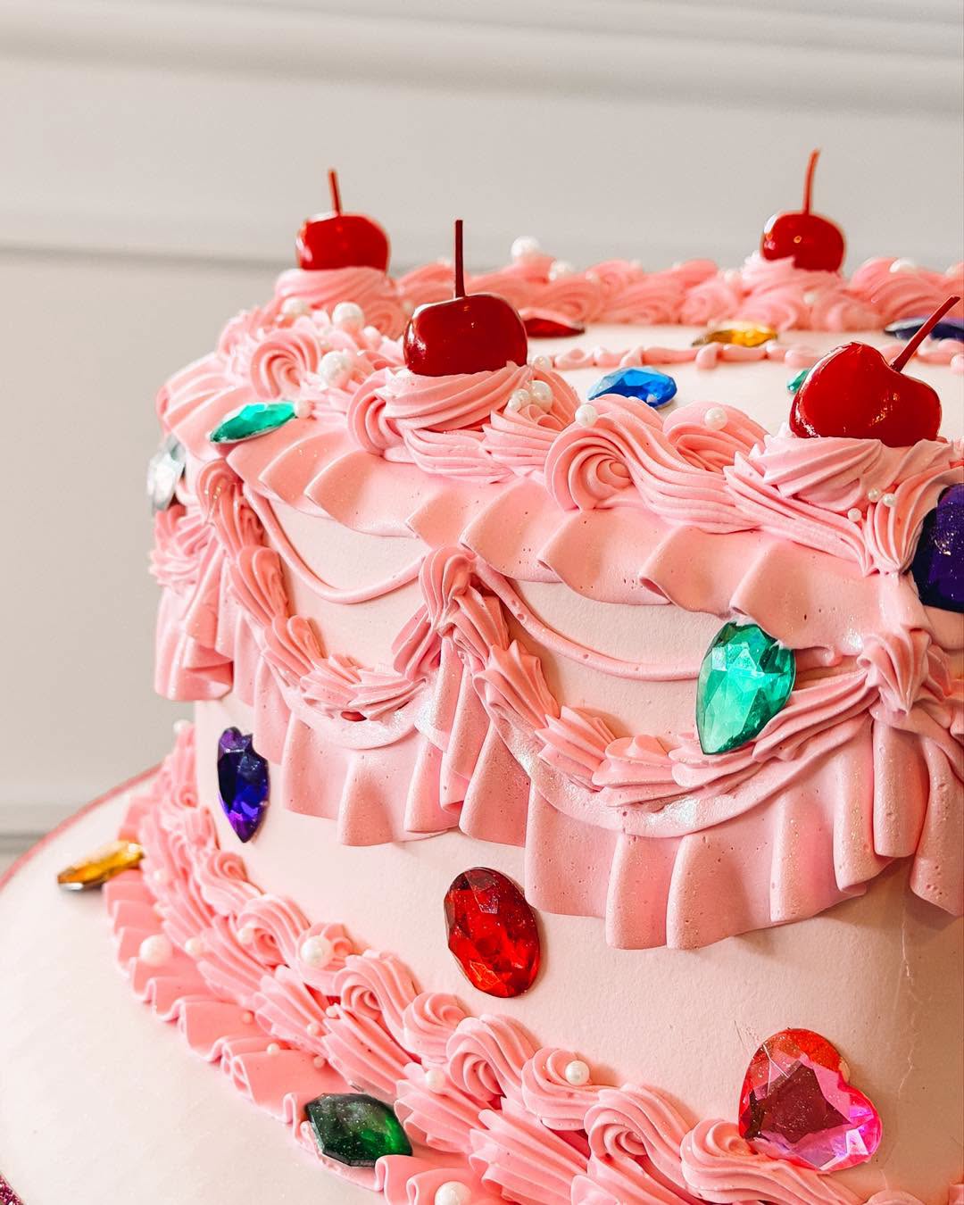 Pink ruffled Ollie's celebration cake with cherries and jewel decorations